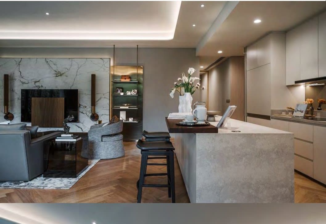 Open kitchen with a pale stone island, black bar stools and a book-matched marble living wall with slatted timber behind.