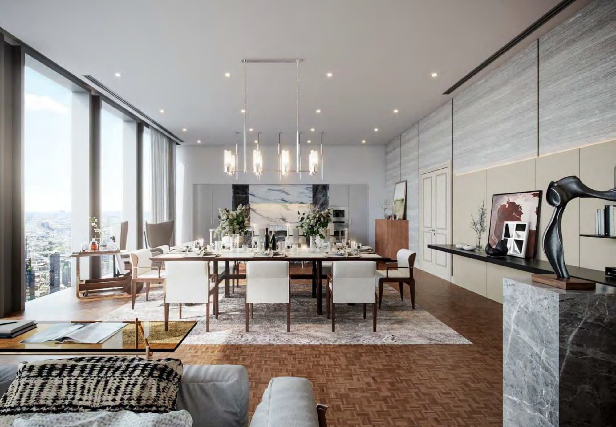 Open dining area with a long walnut table set for dinner beneath a linear brass chandelier, book-matched marble kitchen and distant city view.