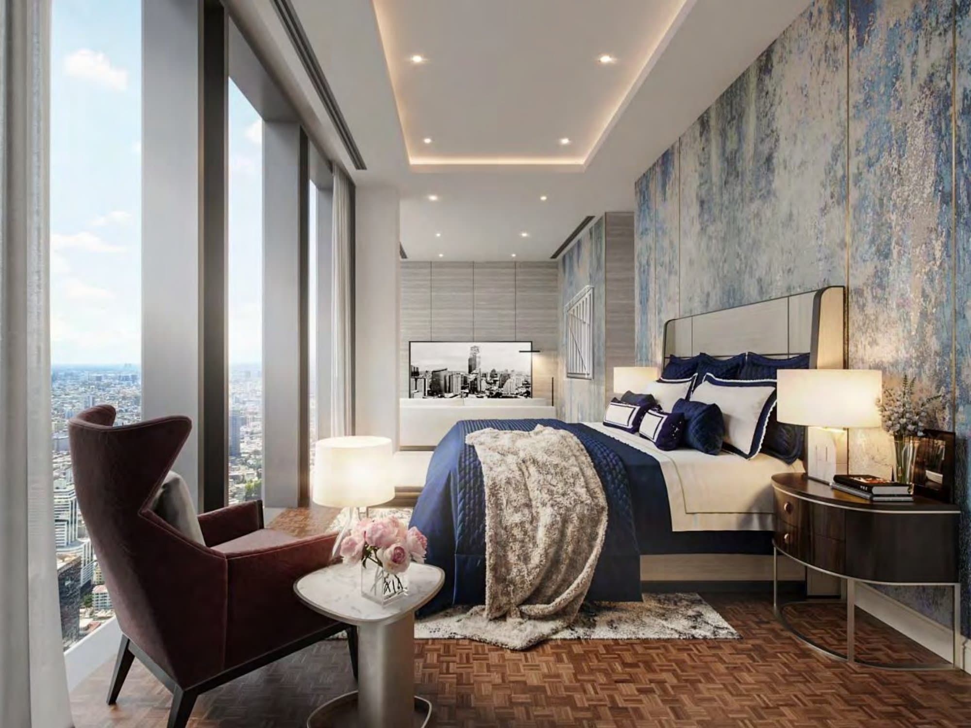 Bedroom in navy and cream against an oxidised blue-and-gold mural wall, with a burgundy wingback chair and floor-to-ceiling skyline windows.