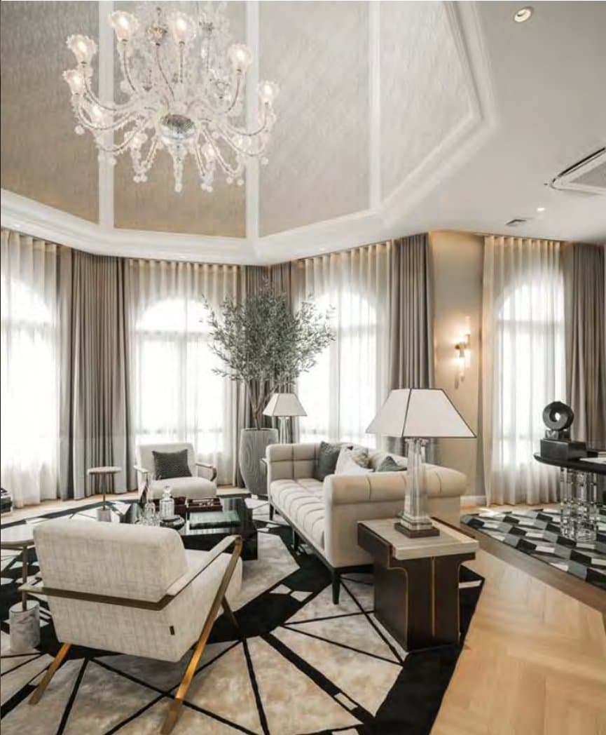 Formal salon with a crystal chandelier, tall arched windows in layered sheers, a tufted cream sofa and a bold black-and-white geometric rug.