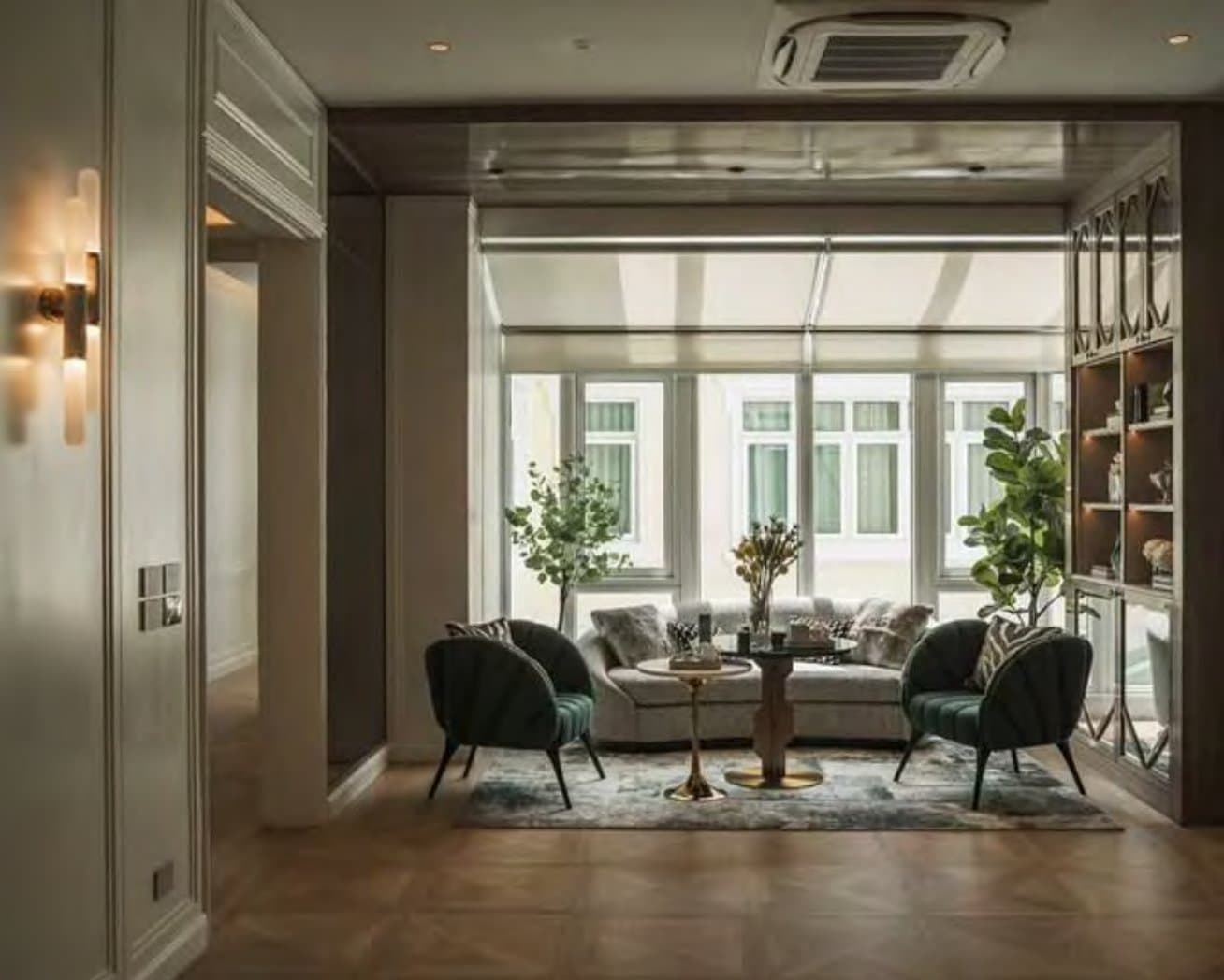 Garden-view sitting room with deep-green velvet shell chairs, a low cream sofa, potted fig trees and blind-filtered windows.