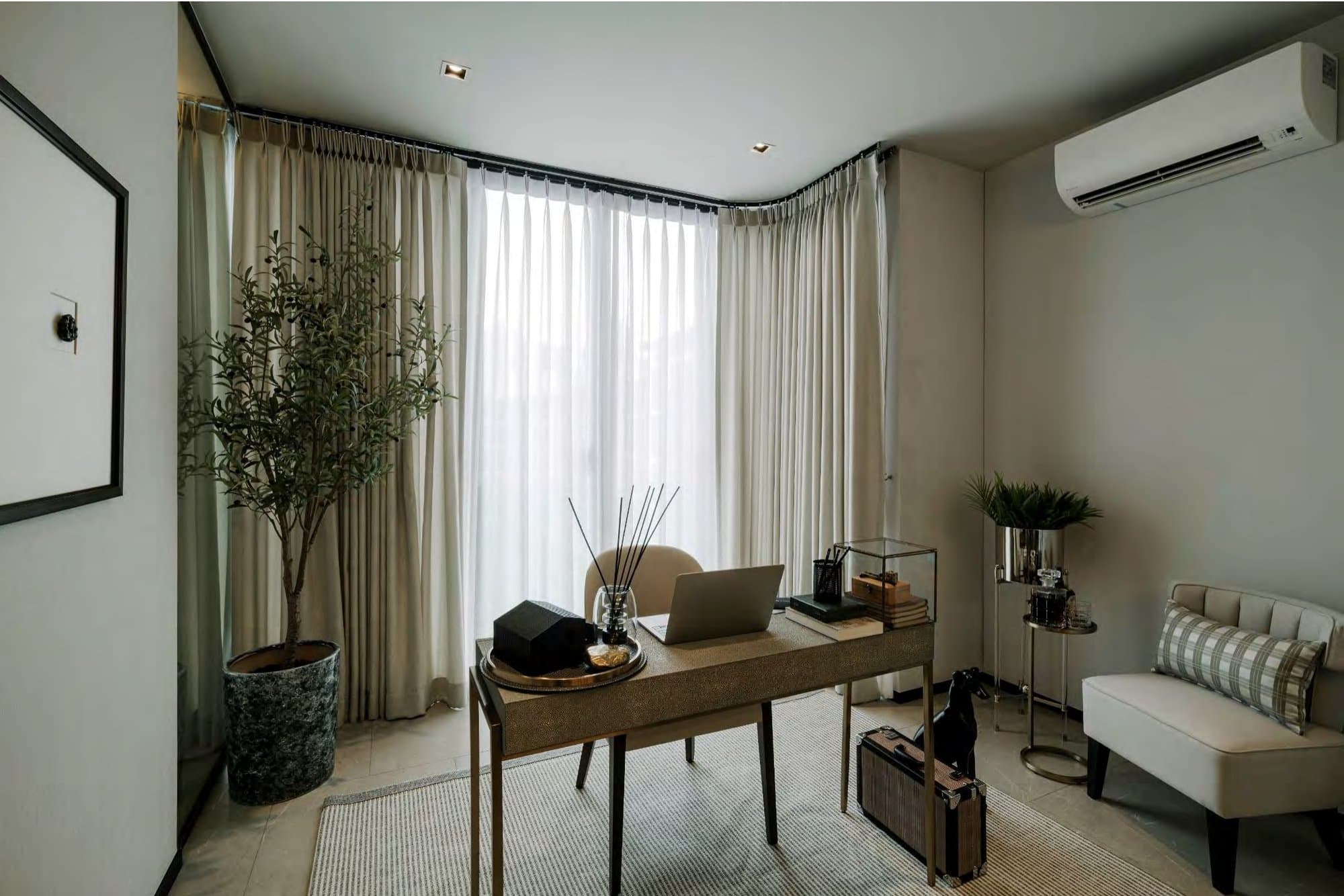 Compact home study with a shagreen-topped desk, laptop, potted olive tree and a slipper chair beside sheer-curtained corner windows.