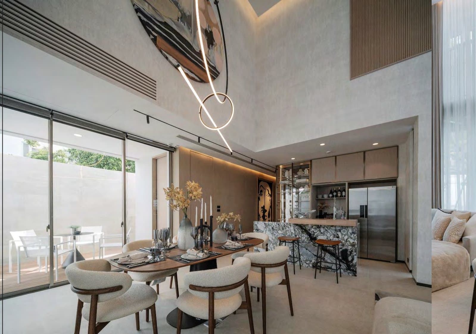 Open-plan dining and kitchen with walnut table, boucle chairs, veined marble island and glass sliders opening to a planted terrace.
