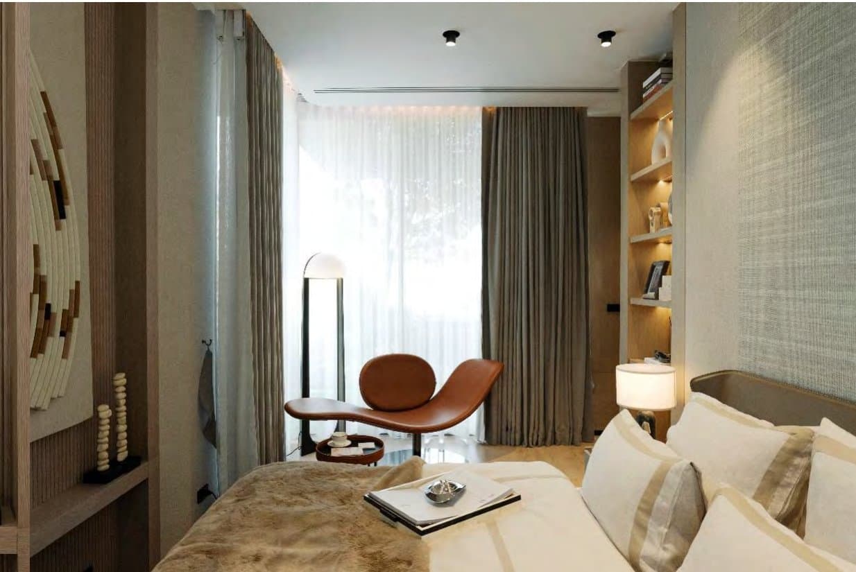 Warm bedroom with tan leather chaise, fur-throw bed, layered linen, woven circular wall art and sheer-filtered daylight.