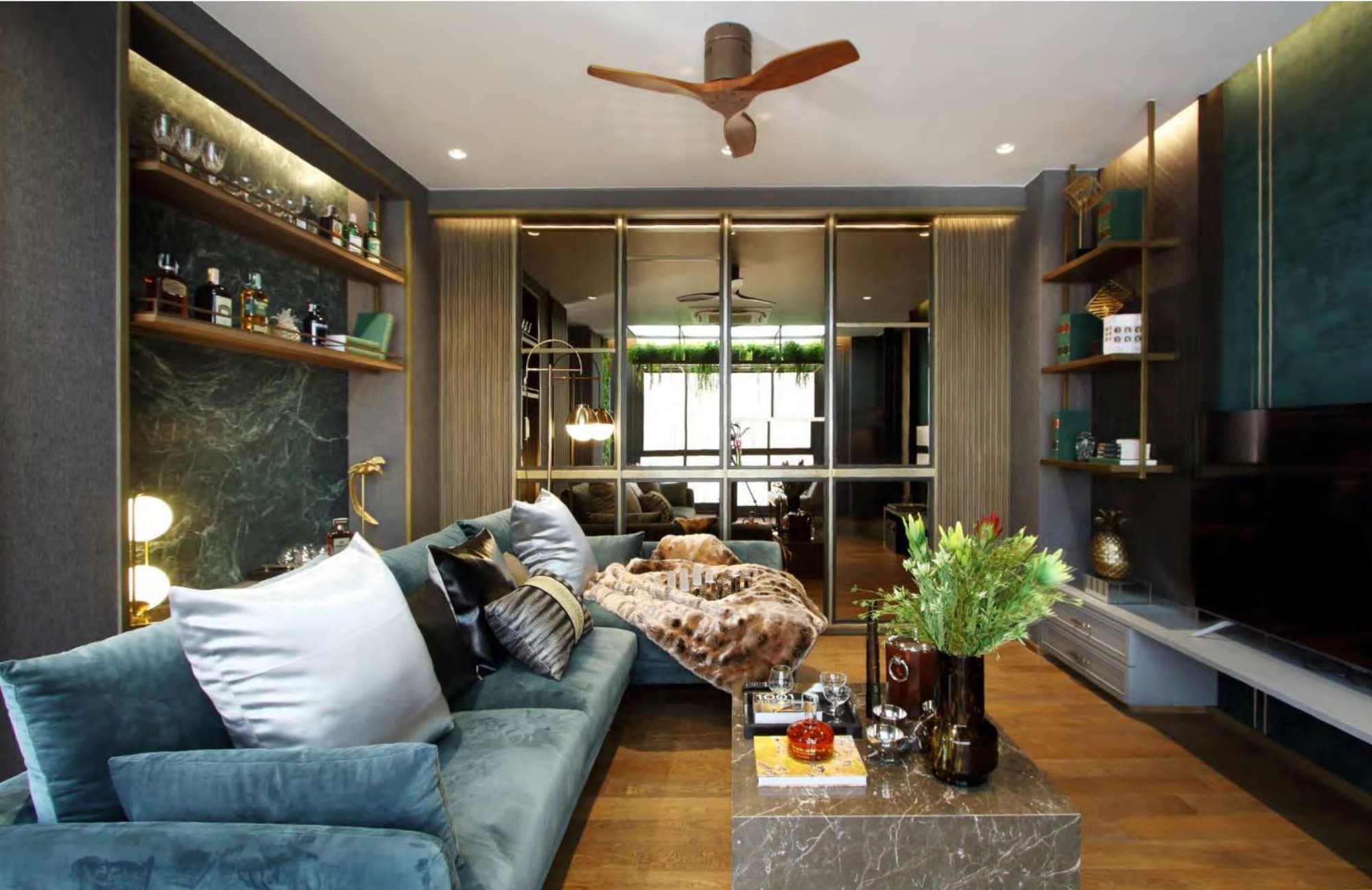 Teal velvet sofa and family den with a green-marble drinks niche, mirrored doors, timber ceiling fan and brass-edged shelving