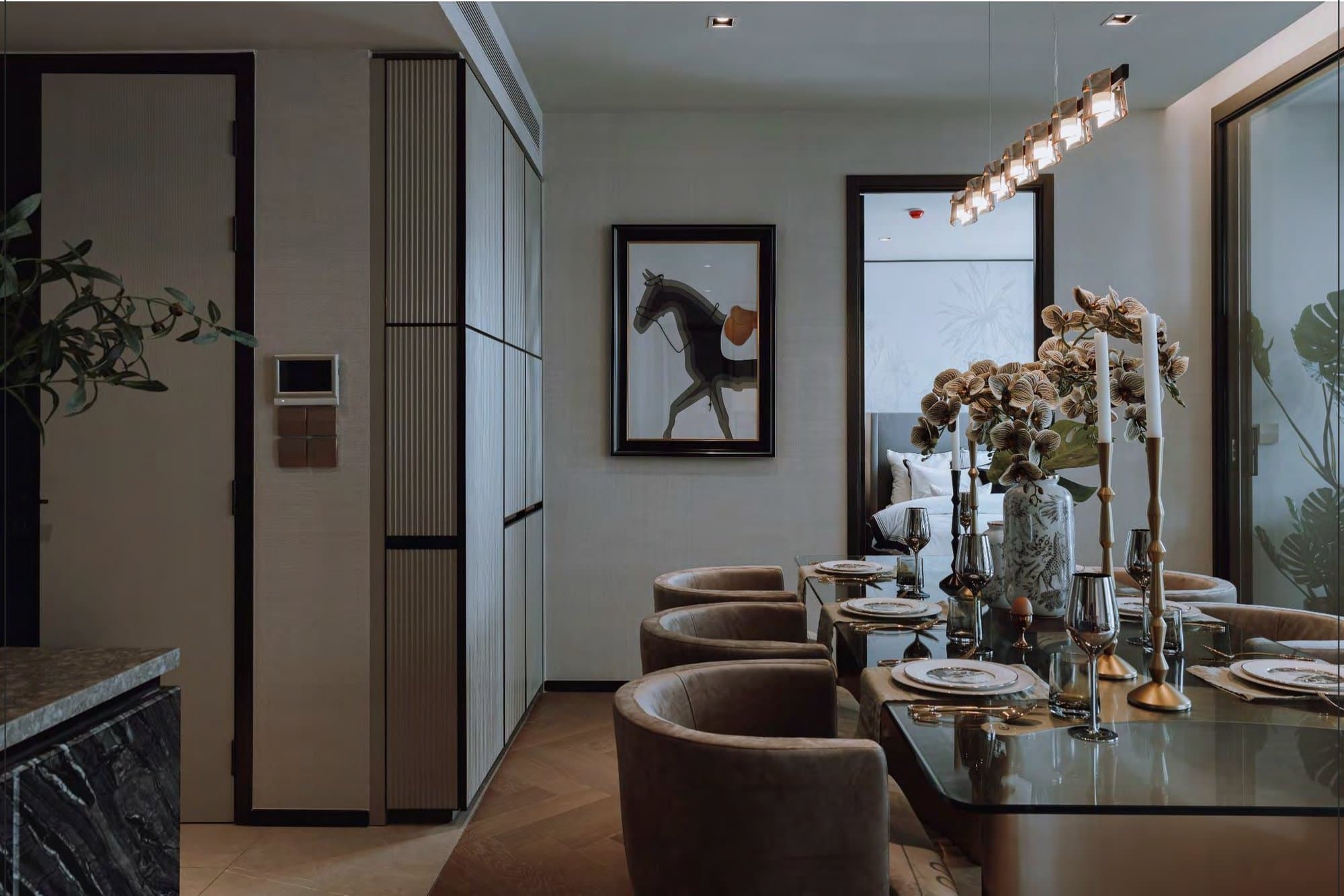 Dining nook with velvet tub chairs, a mirrored table set with gold candlesticks and orchids, beneath a framed equestrian print