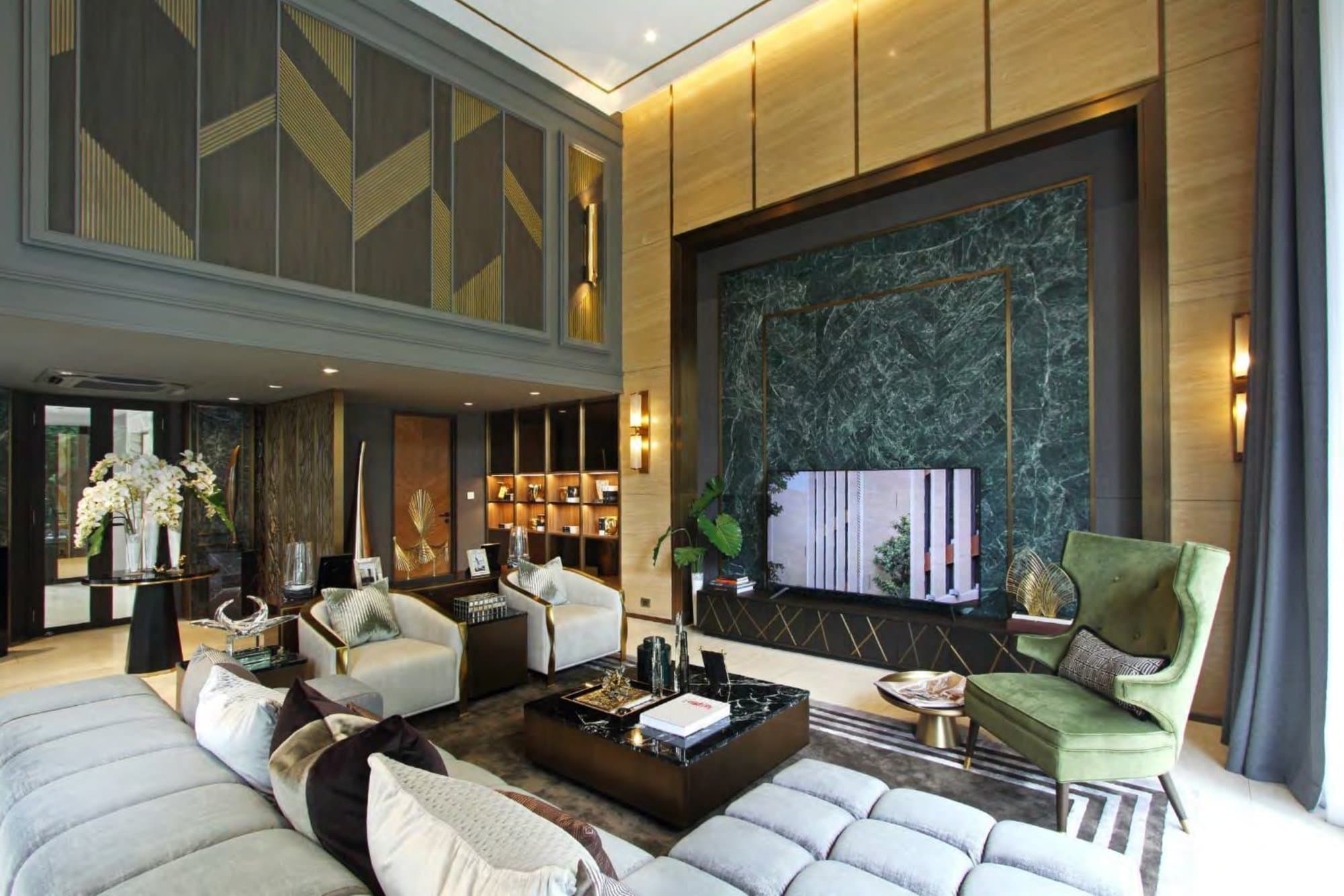 Double-height living room with a green-marble feature wall framed in brass, cream tub chairs, olive velvet armchair and gold-chevron panelling